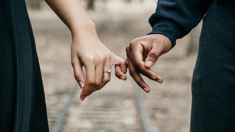 Engaged couple, hands linked with engagement ring in view