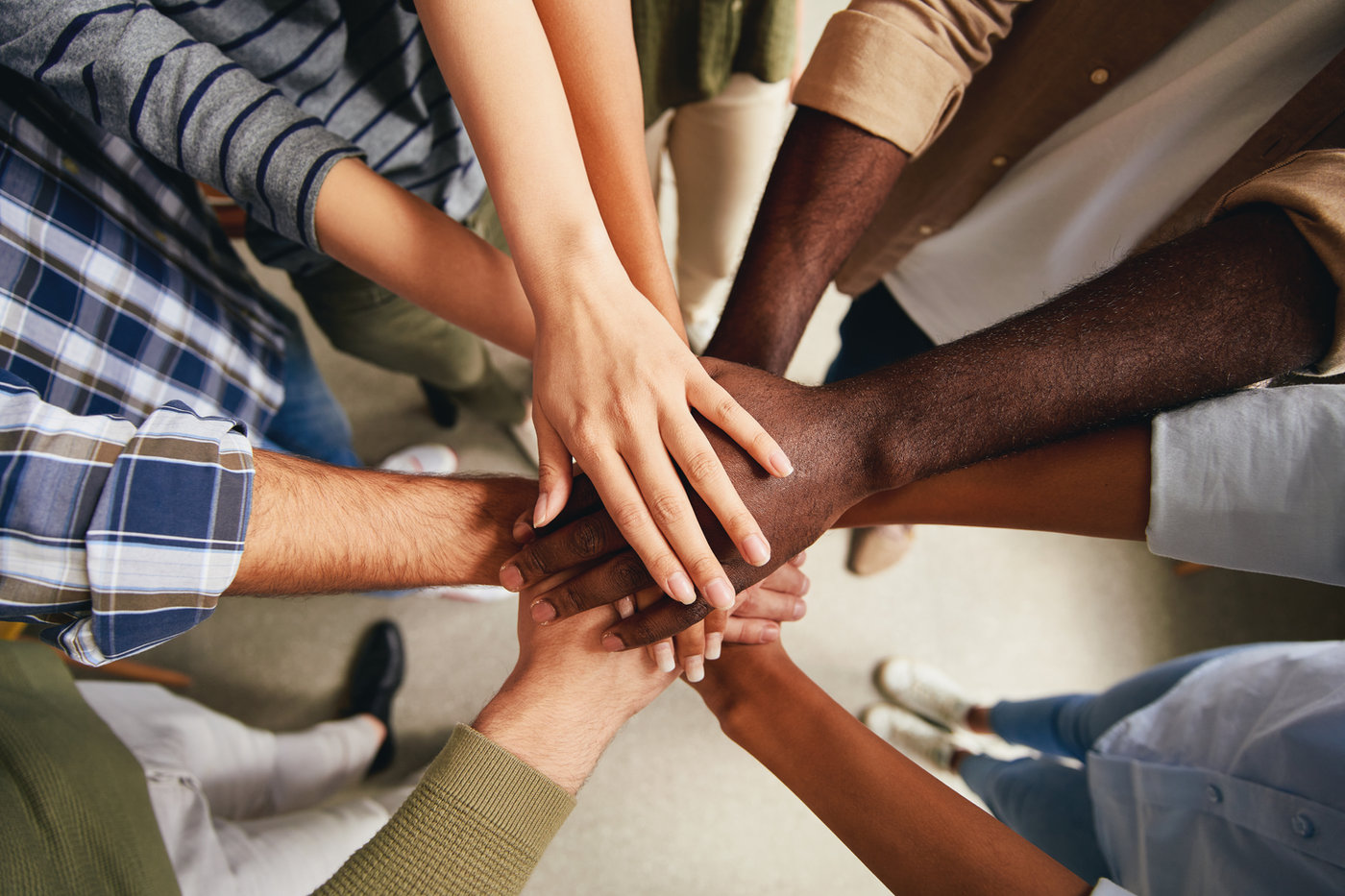 Diverse group of hands stacked together in unity, Love in Action in practice